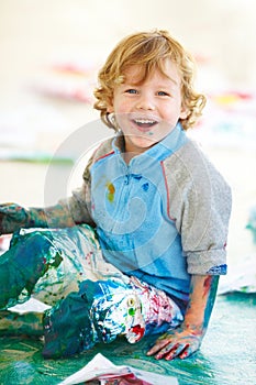 Portrait, art and a boy painting on the floor of a studio for creative expression or education at school. Smile, paint