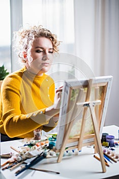 Portrait of an artist girl who creates a painting at home