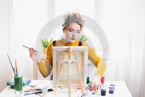 Portrait of an artist girl who creates a painting at home