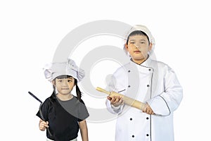 Portrait asia, healthy boy & girl in a kitchen white uniform and chef hat holding wooden rolling pin & spatula equipment for