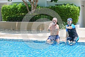 Portrait asia senior woman and caucasian old man resting together in the edge of swimming pool in clubhouse