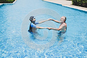 Portrait asia senior woman and caucasian old man resting together in the edge of swimming pool in clubhouse