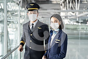 Portrait of Asian airliner pilot and air hostess wear mask and smile. Attractive man and woman captain and cabin crew stewardess