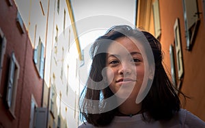 Portrait of Asian American teen standing in front of old buildings smiling