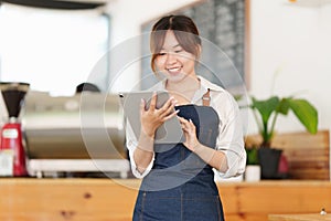 Portrait of Asian Barista cafe owner with tablet to check order. SME entrepreneur seller business concept.