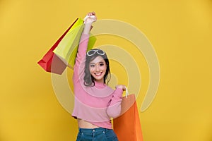 Portrait Asian beautiful happy young woman smiling cheerful and holding shopping bags isolated on yellow studio background.