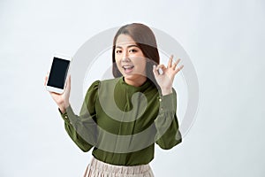 Portrait Asian beautiful happy young woman standing smile, holding mobile phone and showing ok gesture