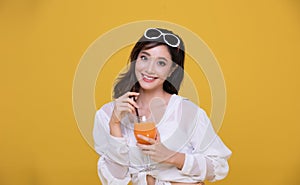 Portrait Asian beautiful happy young woman with sunglasses  smiling cheerful and Holding a glass of orange juice in summer and