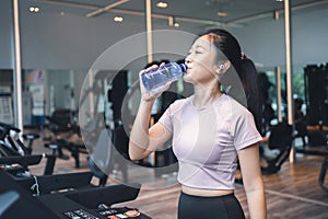 Portrait asian beautiful sport woman wearing sportwear on treadmill machine , she drinking water