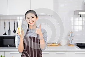 Portrait of asian beautiful woman and housewife is smiling and holding banana in white kitchen. Healthy food concept,Beautiful