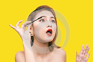 Portrait of Asian Beautiful woman with makeup brush near her face against yellow background