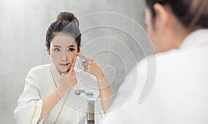 Portrait of asian beautiful woman watch mirror finger touch her face before shower.