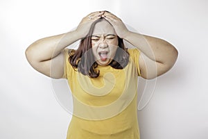 A portrait of an Asian big sized woman wearing a yellow t-shirt isolated by white background looks depressed