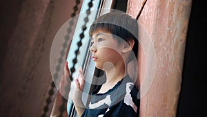 Portrait of Asian Boy Looking out a Daytime Window