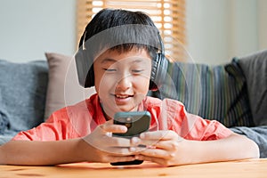 Portrait. Asian boy playing online game on smart phone with headphones . Asia man using mobile phone happy smile at home the