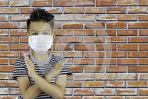 Portrait Asian boy wearing a mask and raised his arms in the shape of a cross background brick wall
