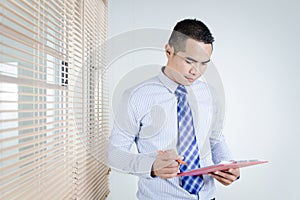 Portrait of asian business man holding clipboard and pen