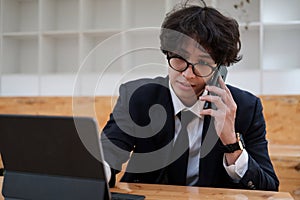 Portrait of asian business man young smiling cheerful entrepreneur in casual office making phone call while working with