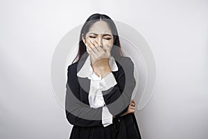 A portrait of an Asian business woman wearing a black suit isolated by white background looks depressed