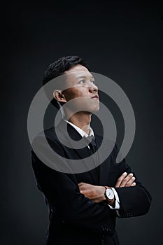 Portrait of Asian Businessman with arms crossed looking up