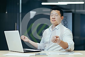 Portrait of Asian businessman, man in office working with laptop, meditating