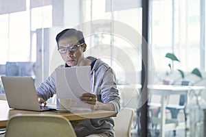 Portrait of Asian businessman working on laptop in office