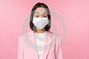 Portrait of asian businesswoman in medical face mask, wearing suit, concept of office work during covid-19 pandemic