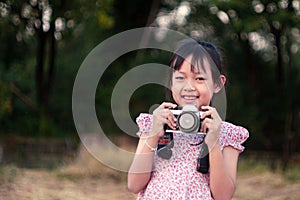 Portrait of asian cheerful little girl taking photo with film camera