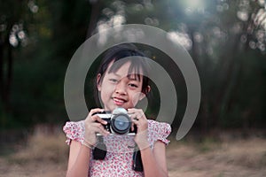 Portrait of asian cheerful little girl taking photo with film camera