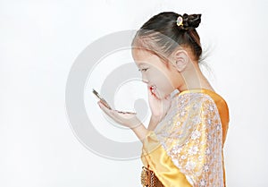 Portrait of asian child girl in traditional thai dress looking at mirror isolated on white background