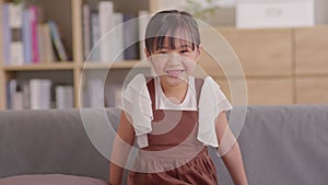 Portrait of asian children smile looking at camera at home.Happiness Little toddler laughing with white teeth on couch in cozy