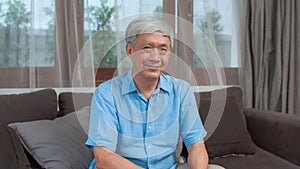 Portrait Asian Chinese senior man feeling happy smiling at home. Older male relax toothy smile looking to camera while lying sofa