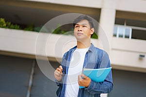 Portrait of a Asian college man student carrying a backpack and standing in a school hallway at campus
