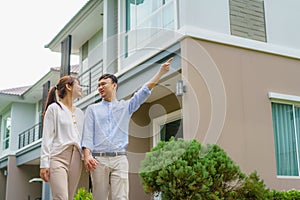 Portrait of Asian couple walking and hugging together looking happy in front of their new house to start new life. Family, age,