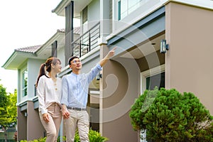 Portrait of Asian couple walking and hugging together looking happy in front of their new house to start new life. Family, age,