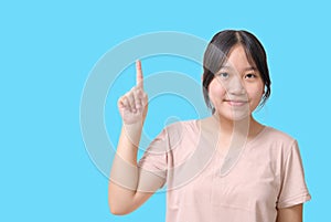 Portrait of Asian cute girl pointing up one hand with finger on upper side with smile face