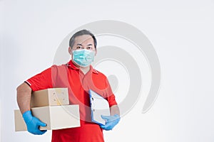 Portrait of Asian delivery man with face medical mask in red cloth holding a box package.
