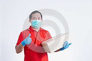 Portrait of Asian delivery man with face medical mask in red cloth holding a box package.