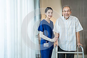 Portrait of Asian disabled Senior Elderly male stand with walker enjoy stay home nursing care. Beautiful nurse caregiver woman