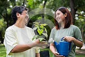 Portrait, Asian family mom and daughter plant sapling tree outdoors in nature park, Concept of happy retirement With care from a