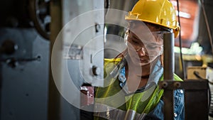 Portrait of asian female mechanic engineer working with steel drilling machine in metal work manufacturing factory