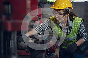 Portrait of asian female mechanic engineer working with steel drilling machine in metal work manufacturing factory