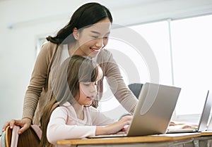 Portrait of Asian female teacher helping schoolgirl is using laptop in computer class.  Education, Elementary school, learning and