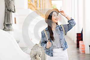 Portrait of Asian female traveler walking on walkway of the temple while smiling back in Bangkok, Thailand, Southeast