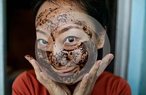 Portrait Of A asian Girl In A Cosmetic Mask Of Coffee. Face Skin Scrub.