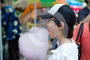 Portrait Asian girl eating the pink cotton candy at the market