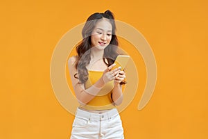 Portrait of asian girl holding smartphone, typing sms message over vivid background