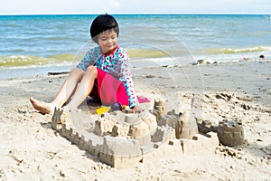 Portrait Asian girl plays on the beach and builds castle