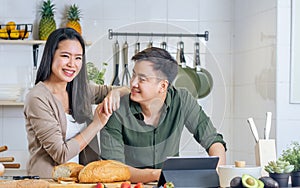 Portrait Asian happy young adult couple lover helping together, holding kitchenware, cooking in cozy home kitchen in morning,