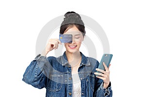 Portrait Asian happy young girl in jeans shirt smiling cheerful and showing plastic credit card while holding mobile phone